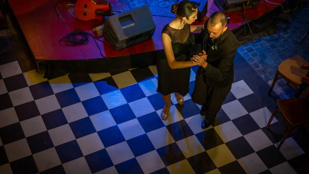 A couple in close embrace on the studio floor during an evening milonga.